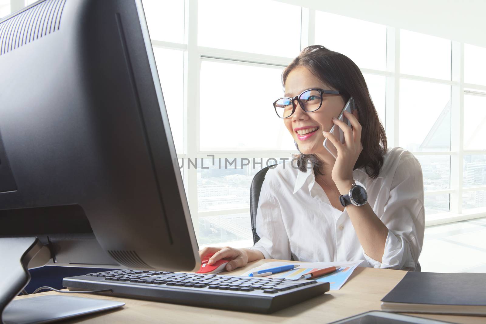young working woman talking to phone with watching on computer o by khunaspix