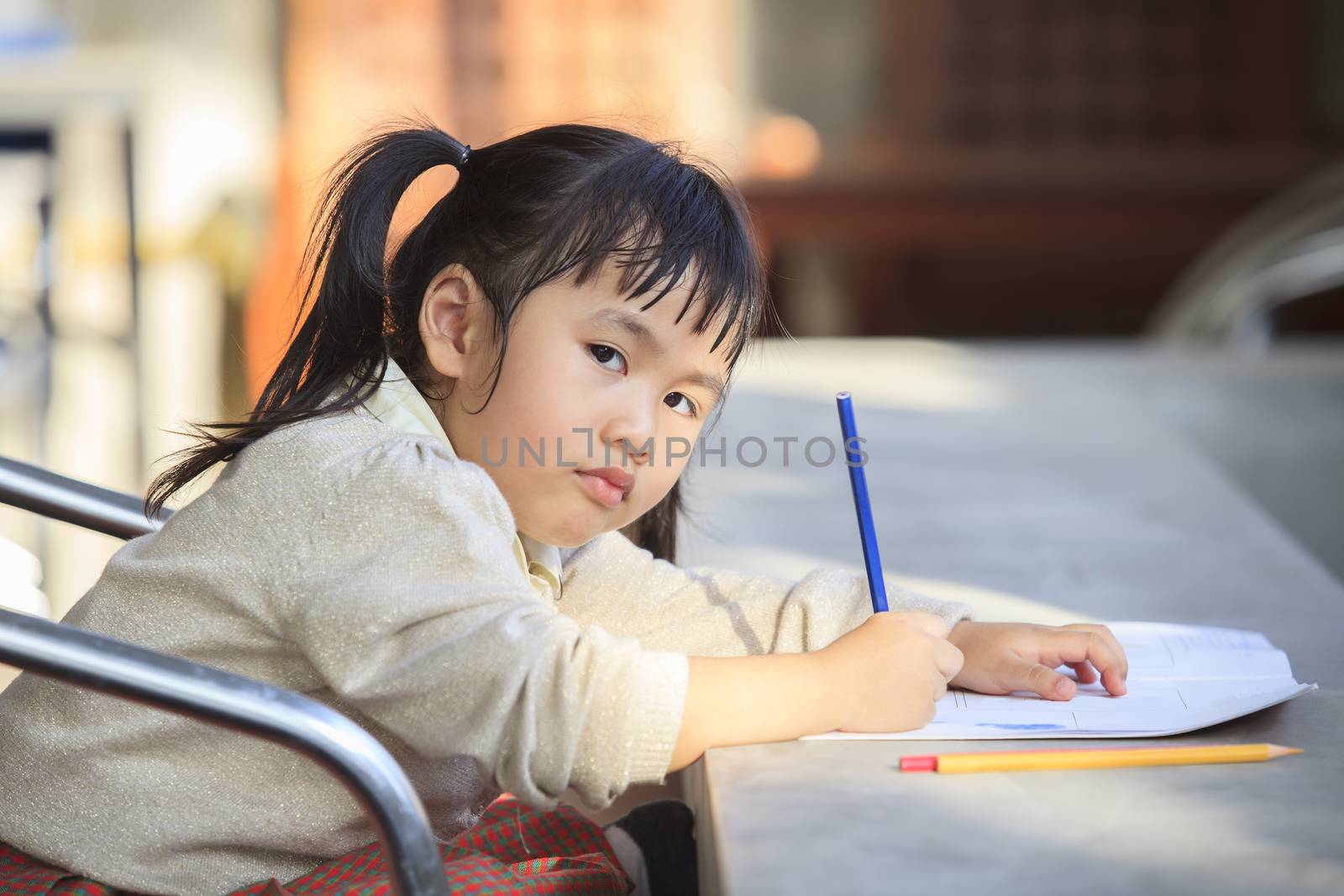 asian children with yellow pencil in hand doing school home work with happiness emotion 