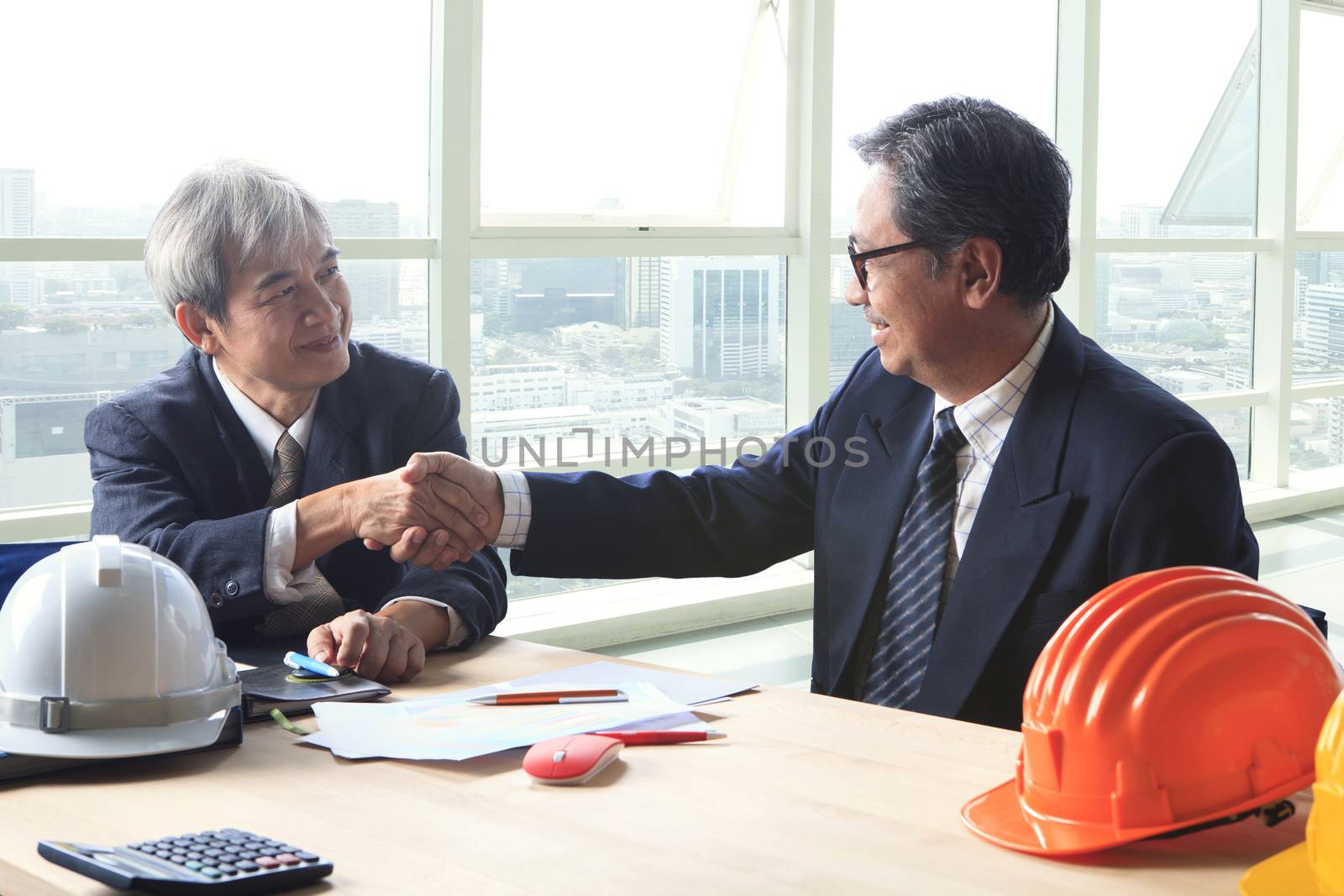 two engineer construction business man shaking hand after projec by khunaspix