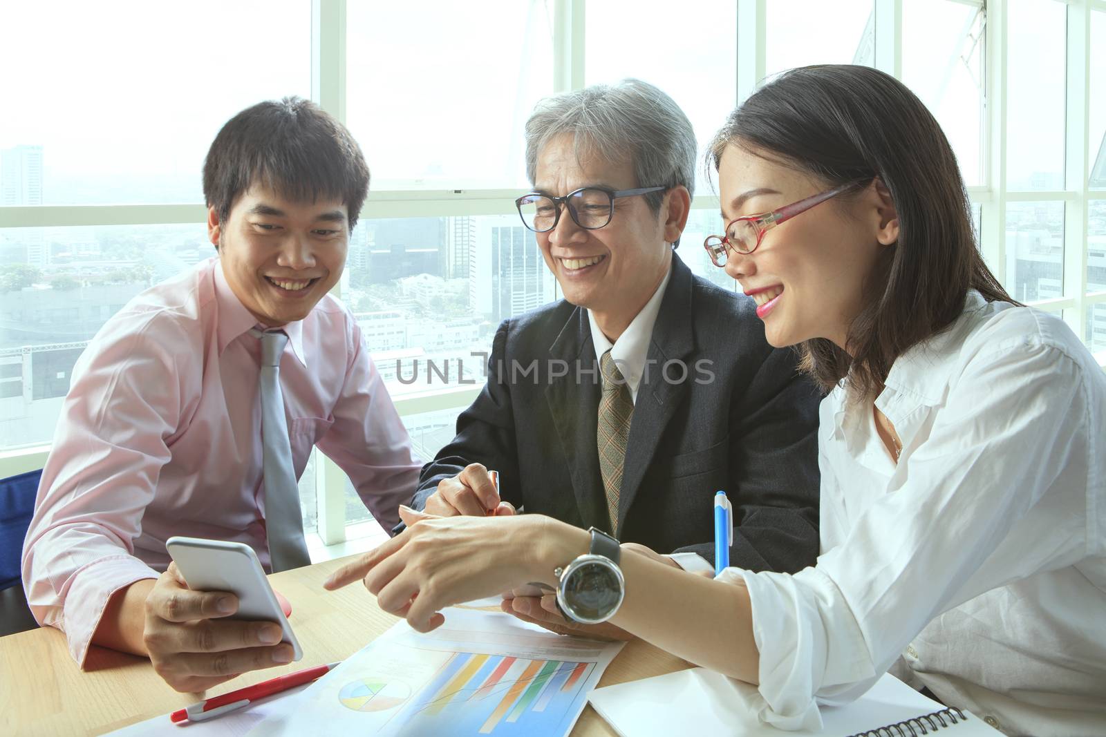 group of business people meeting with happiness emtion pointing to smart phone in hand use for modern working people lifestyle on digital technology