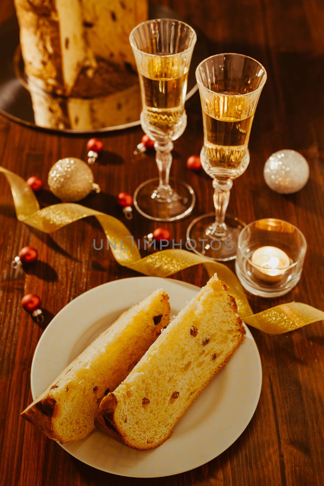 Sliced italian panettone, sparkling wine and decorations over a table seen from above