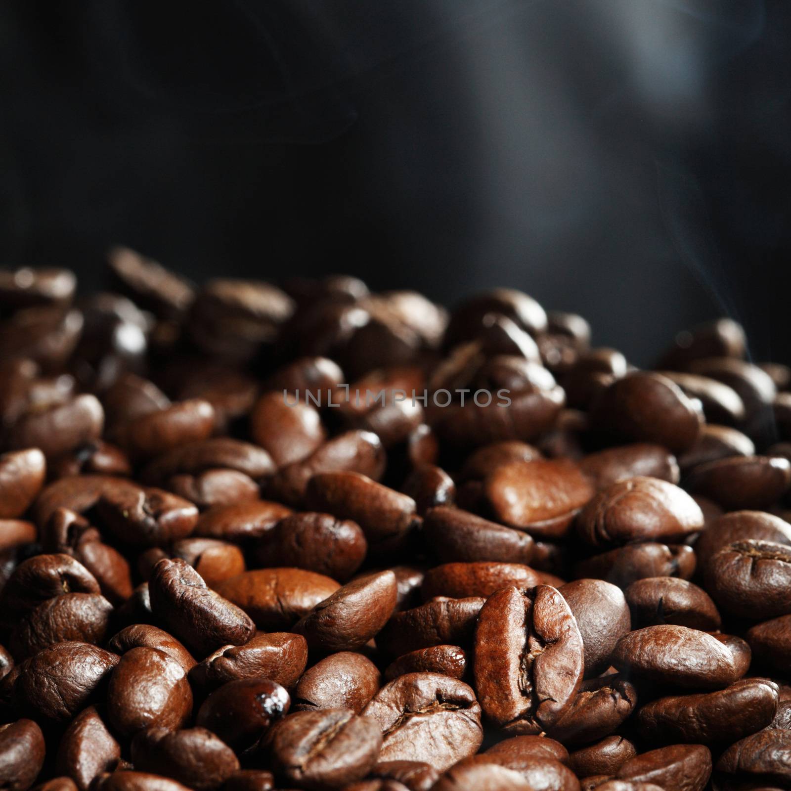 Hot roasted coffee beans and steam on black