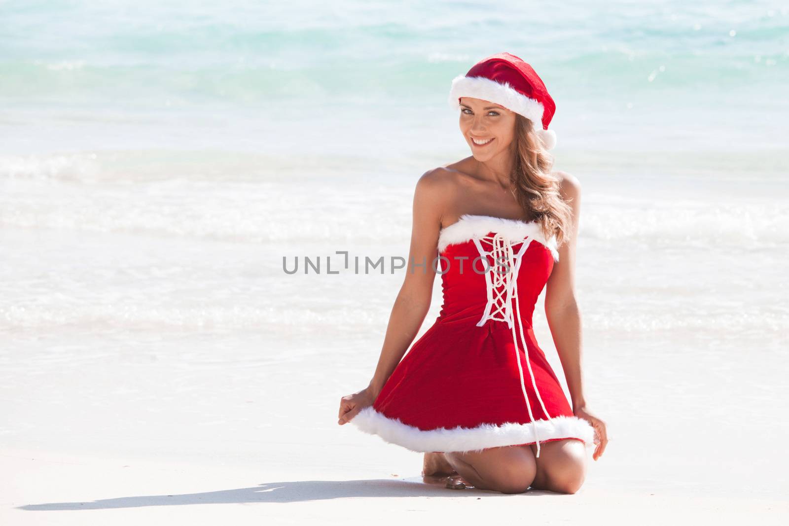 Beautiful woman in Mrs. Claus custume on tropical beach, Christmas vacations concept