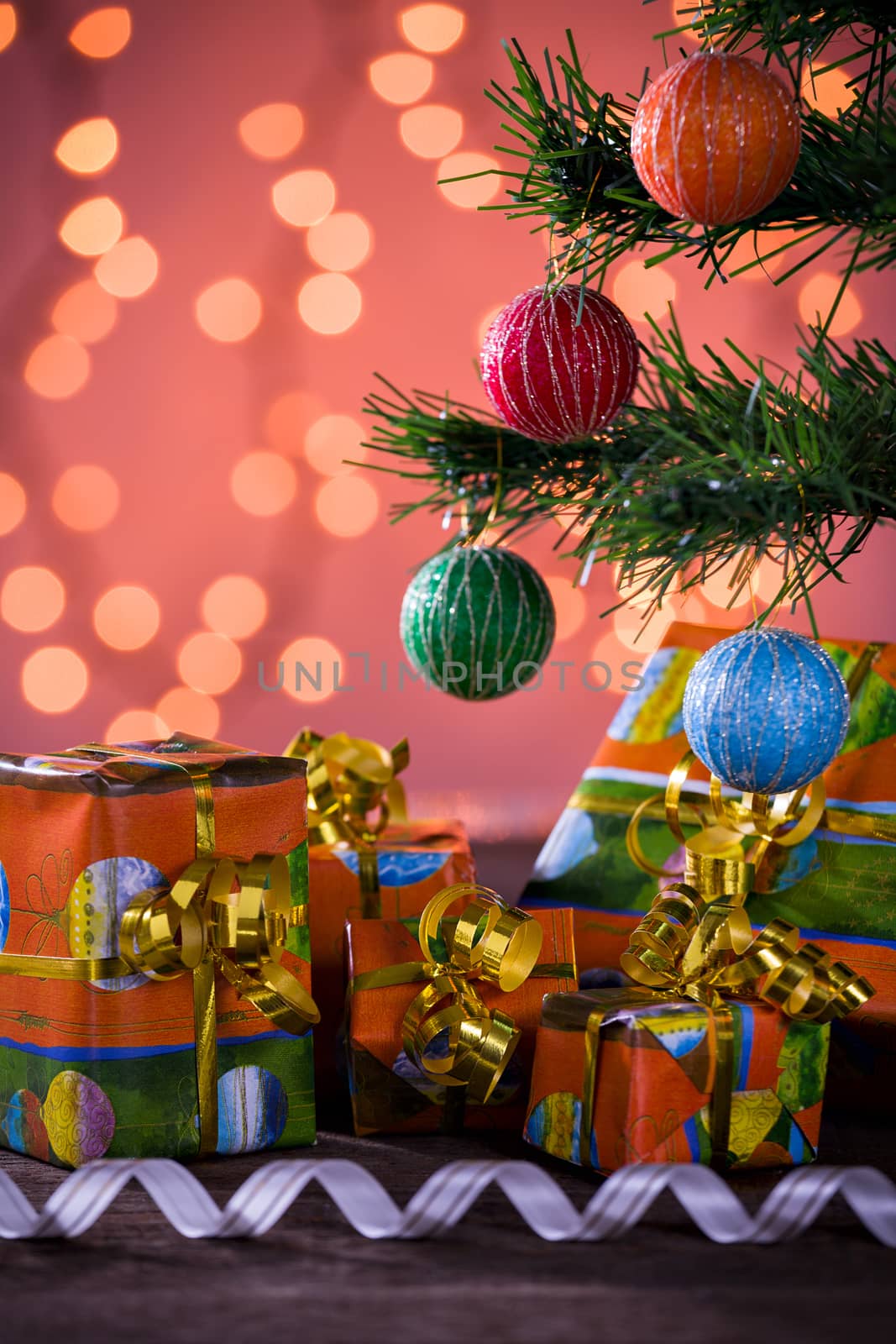 Christmas gifts with blurred lights on background and ribbon under the tree