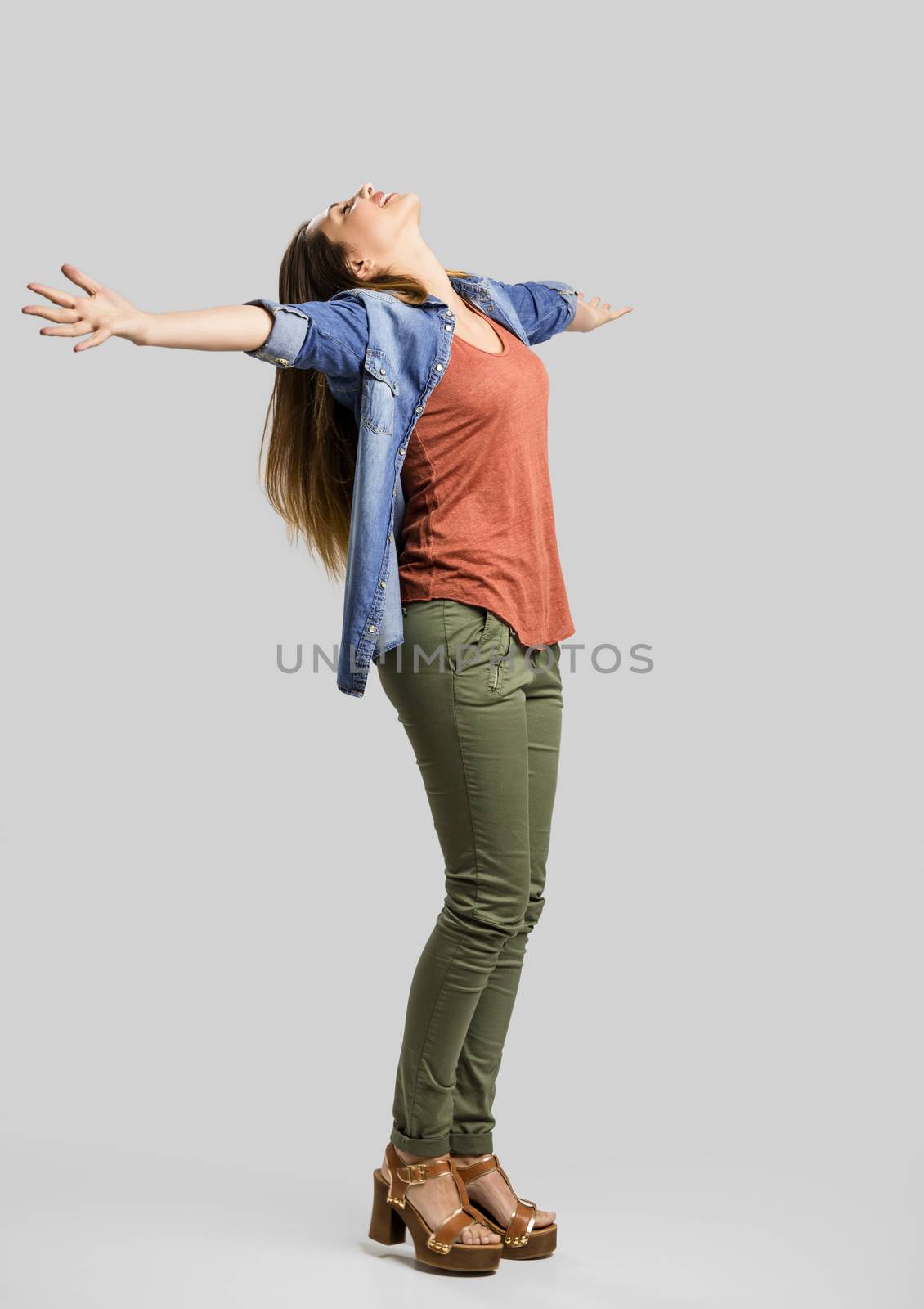 Beautiful happy woman with arms up over a gray background