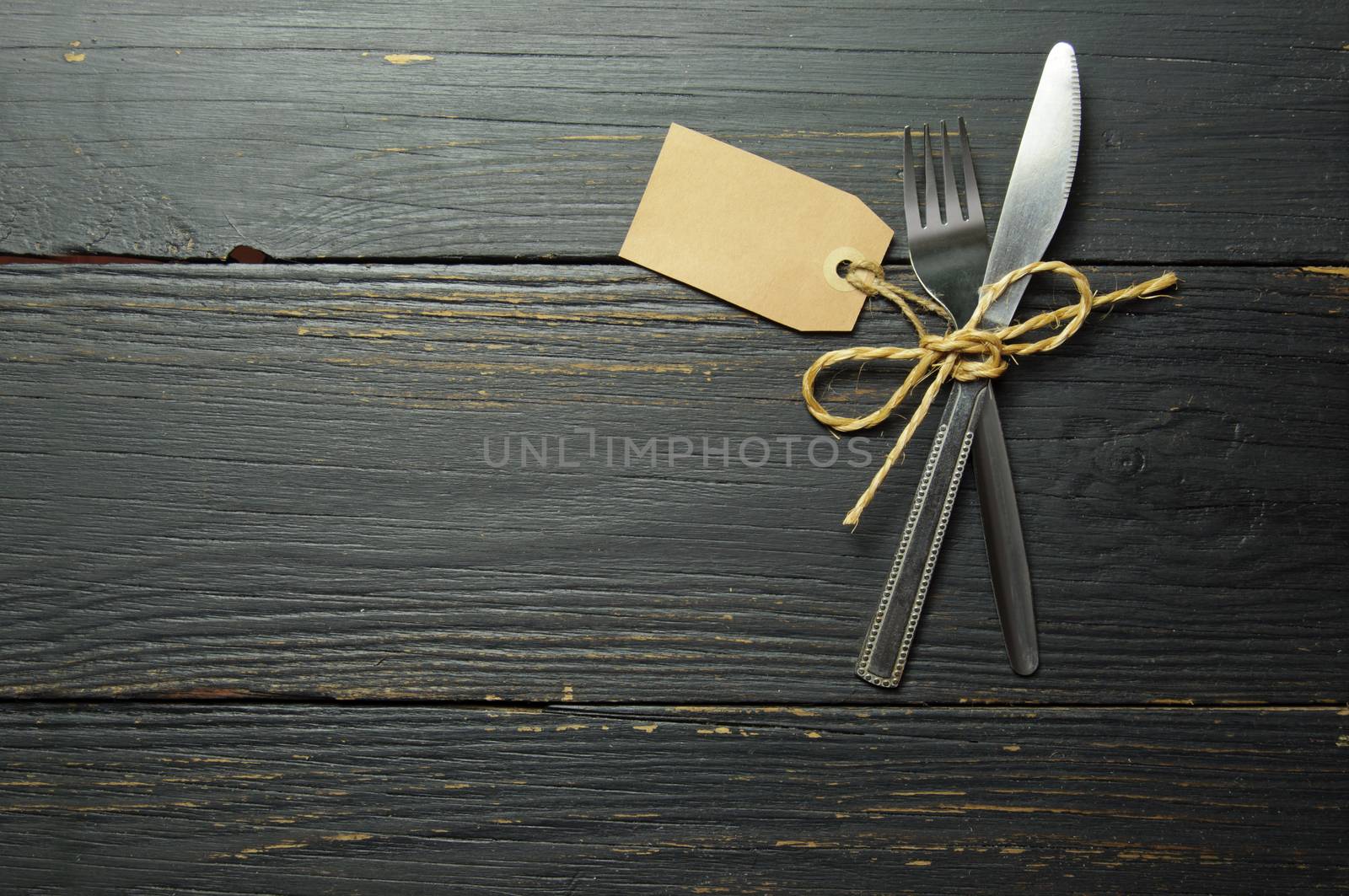 Fork and knife tied together on a wooden table with space 