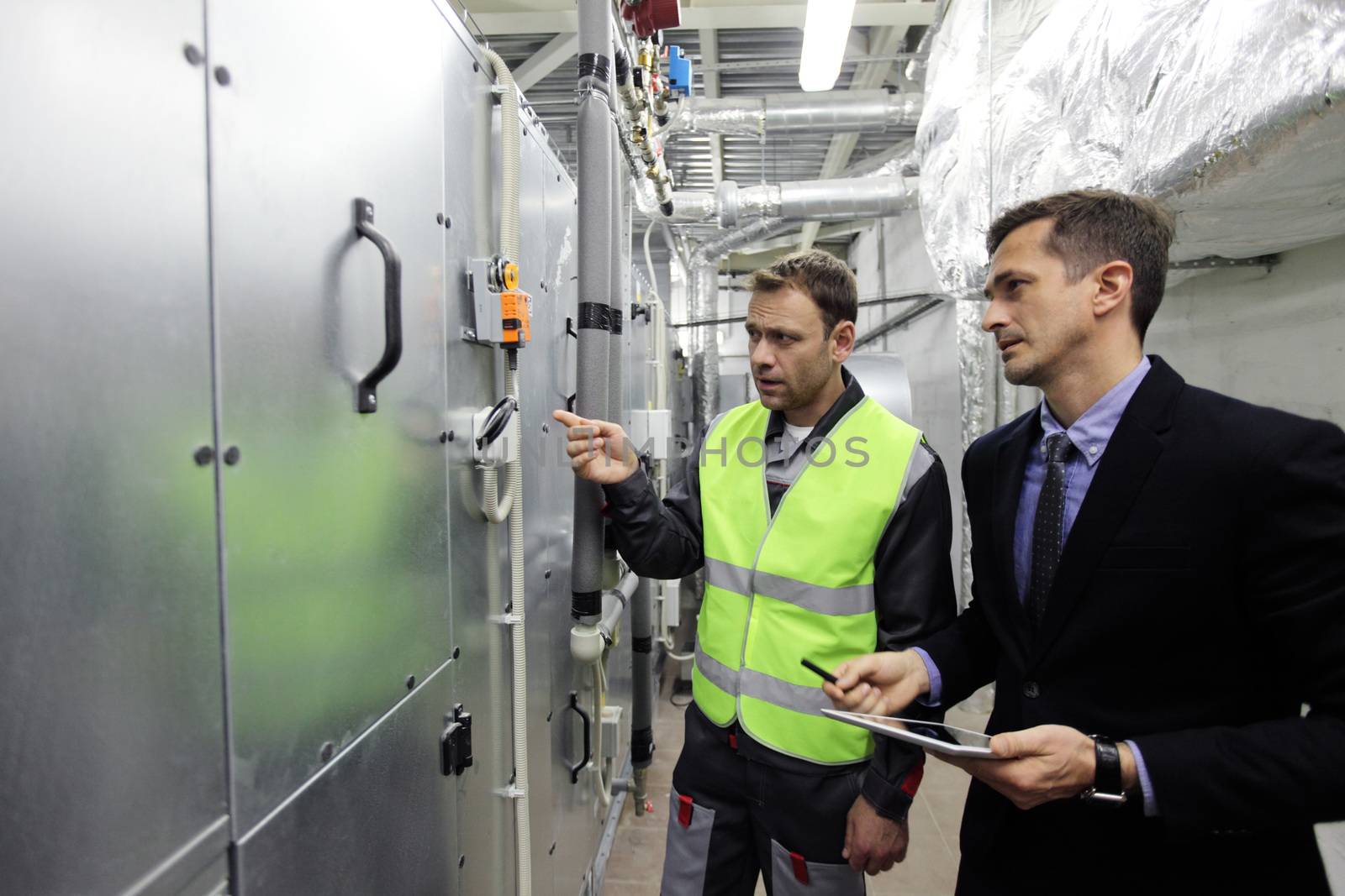 Worker and manager check switchboards at factory auxiliary room