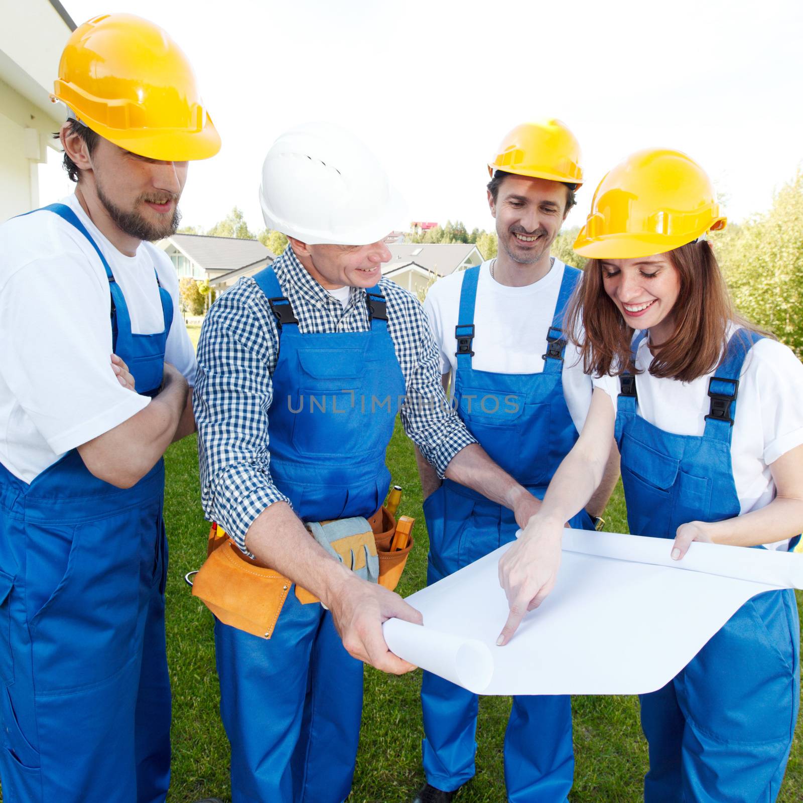 Team of builders with construction plan outdoors