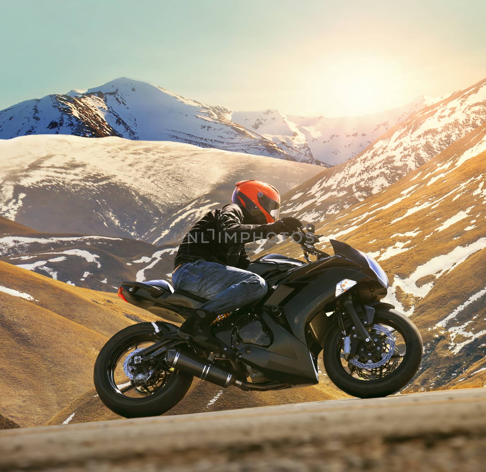 young man riding motorcycle on asphalt country road with sun shining and mountain background use for sport activities,male leisure and journey theme