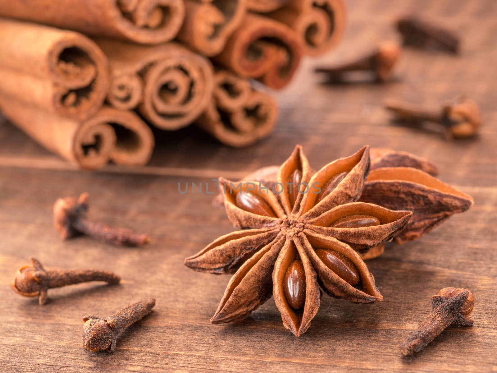 star anise on wooden background close up. Blurred clove and cinnamon sticks as background