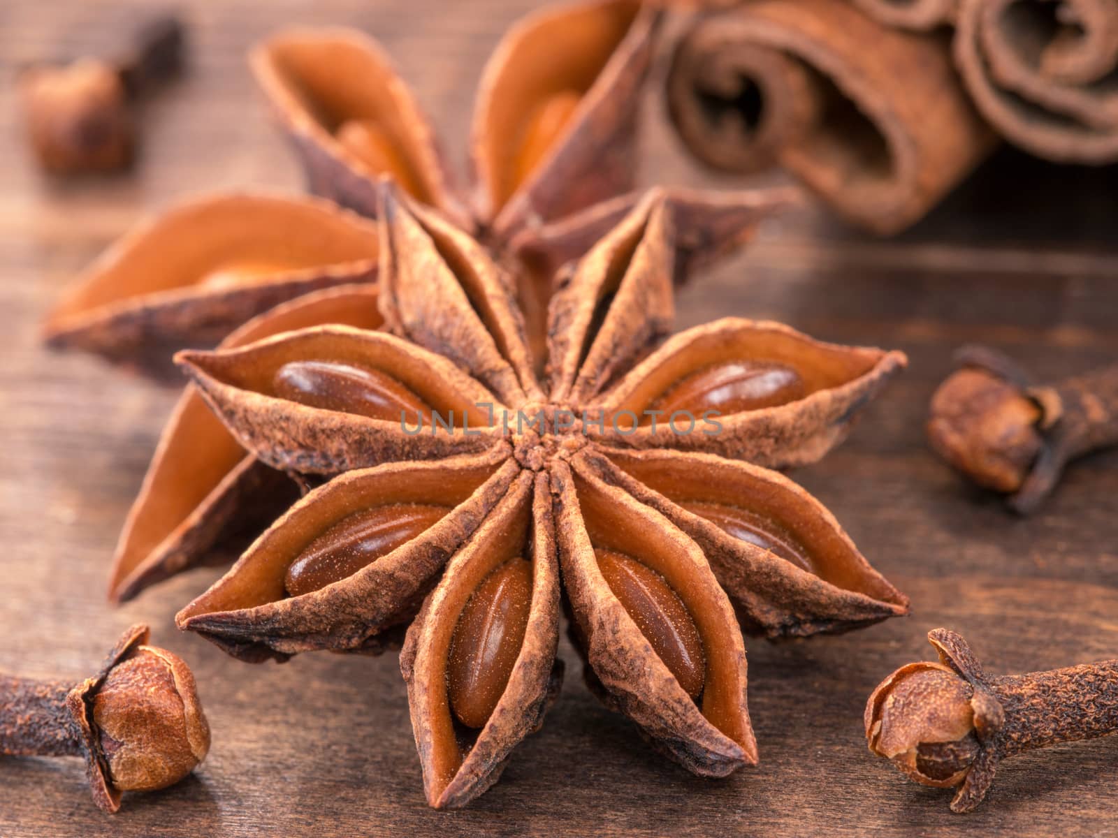 star anise on wooden background close up. Blurred clove and cinnamon sticks as background
