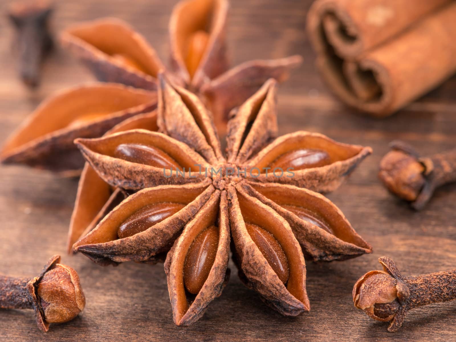star anise on wooden background close up. Blurred clove and cinnamon sticks as background