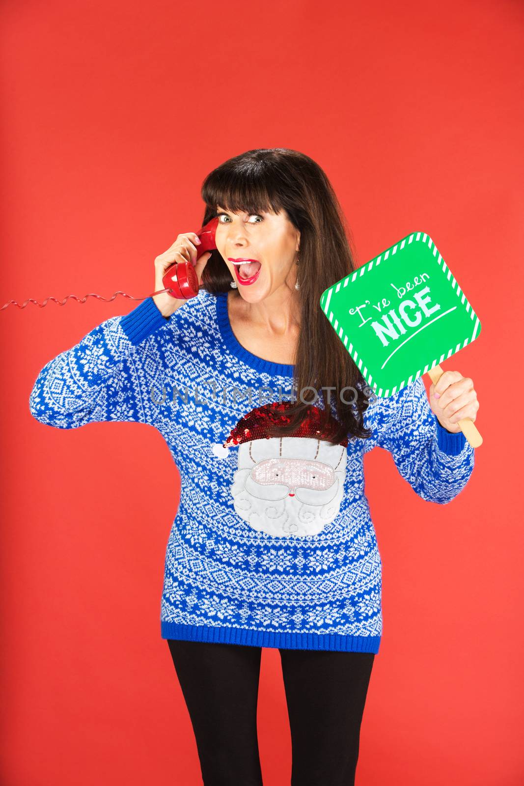 Excited woman on phone holding sign about nice behavior over red