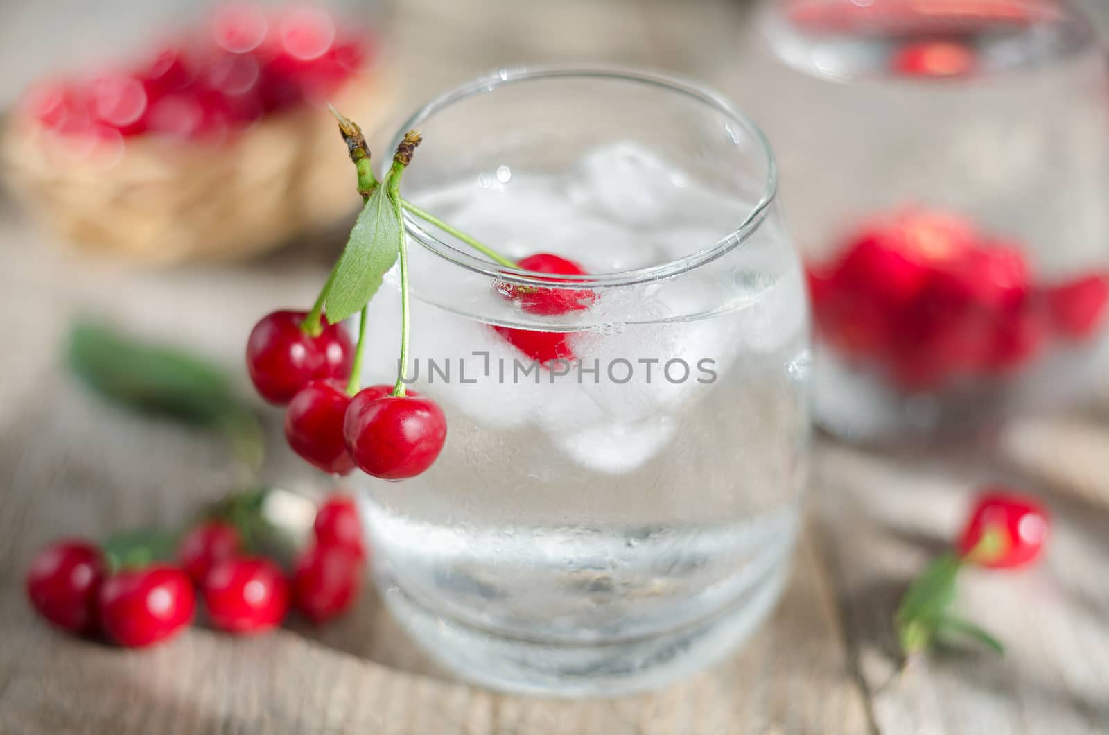 Cold water with ice and cherries. Morning light, the surface of unplaned planks and side. Selective focus.