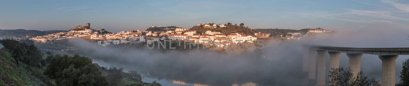 Wide view of Mertola village engulfed on a foggy morning.