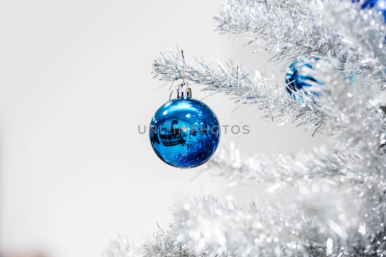 Blue baubles hanging on silver artificial christmas tree, good as background