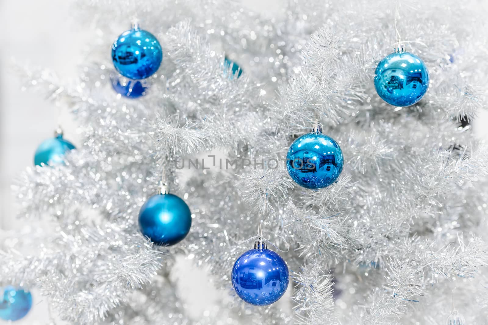 Blue baubles hanging on silver artificial christmas tree, good as background