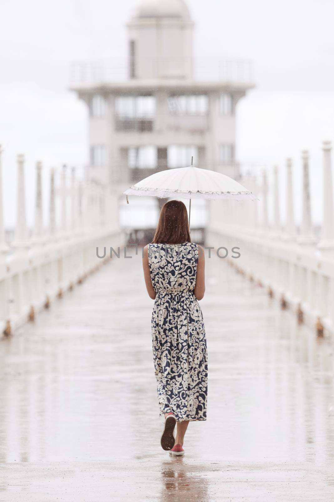 woman and umbrella walking on jett bridge in raining day