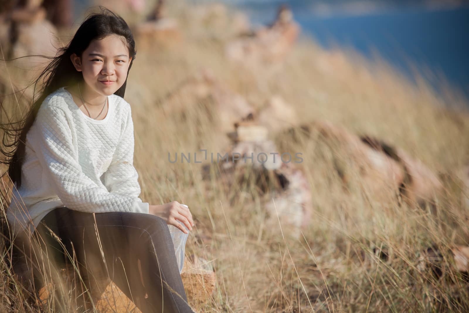 portrait of asian girl relaxing emotion sitting in grass field and windy evening use for teen age leisure and activities traveling vacation time