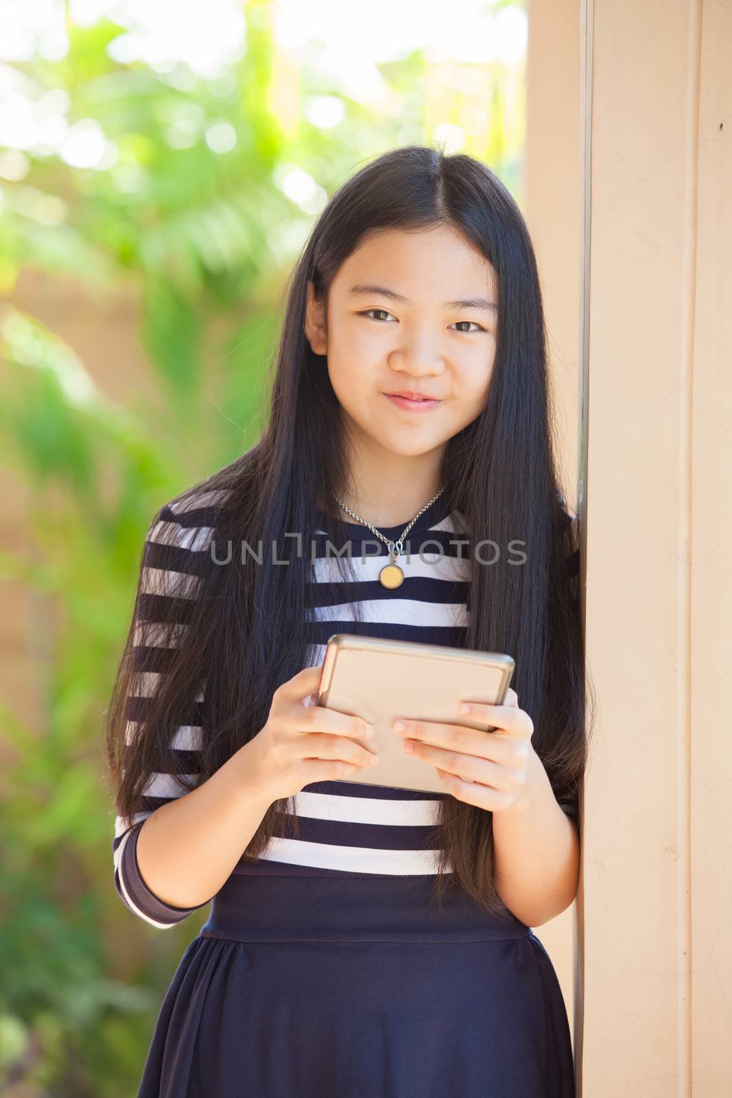 twelve years old asian kid standing with happiness smiling face and tablet computer in hand use for modern life of education and livestyle