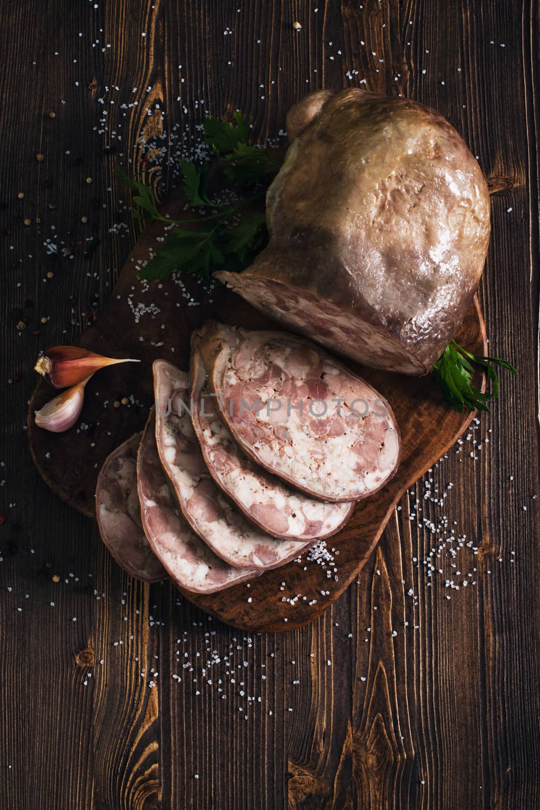 Sliced pork saltisons with herbs on a slate cutting board on wooden background