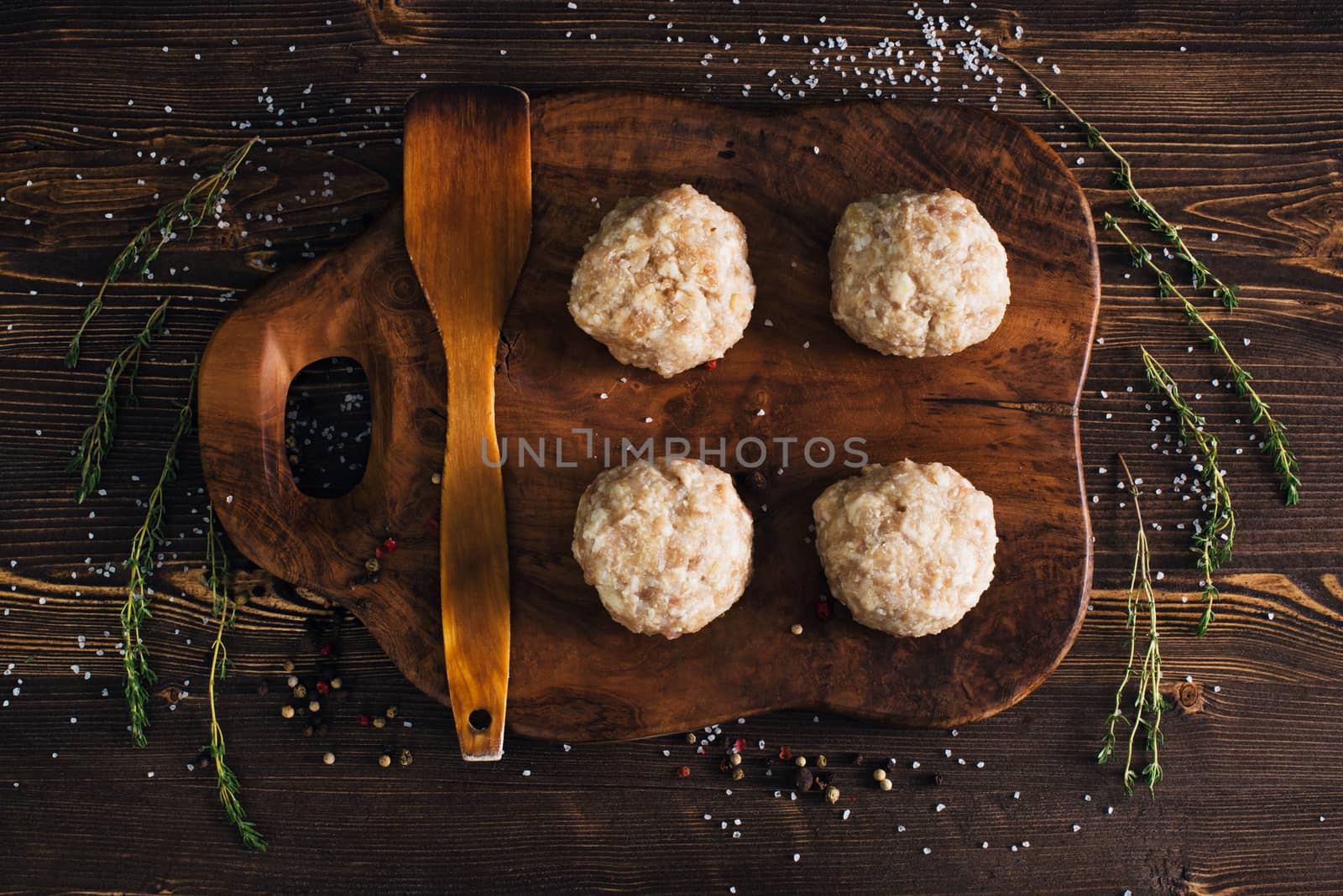 Uncooked meatballs on a dark wooden board by kzen