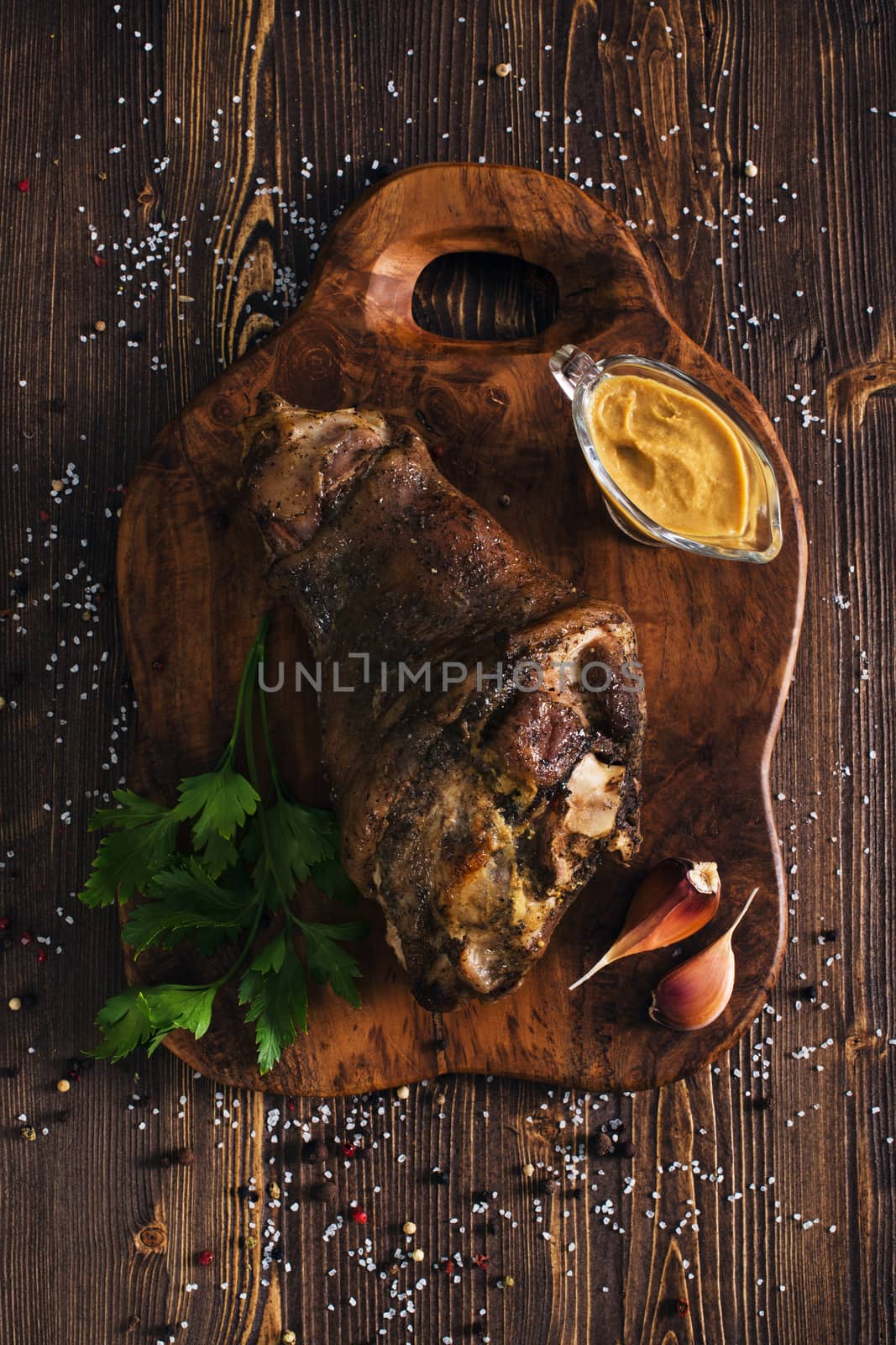 Whole roasted pork knuckle with mustard, wooden background