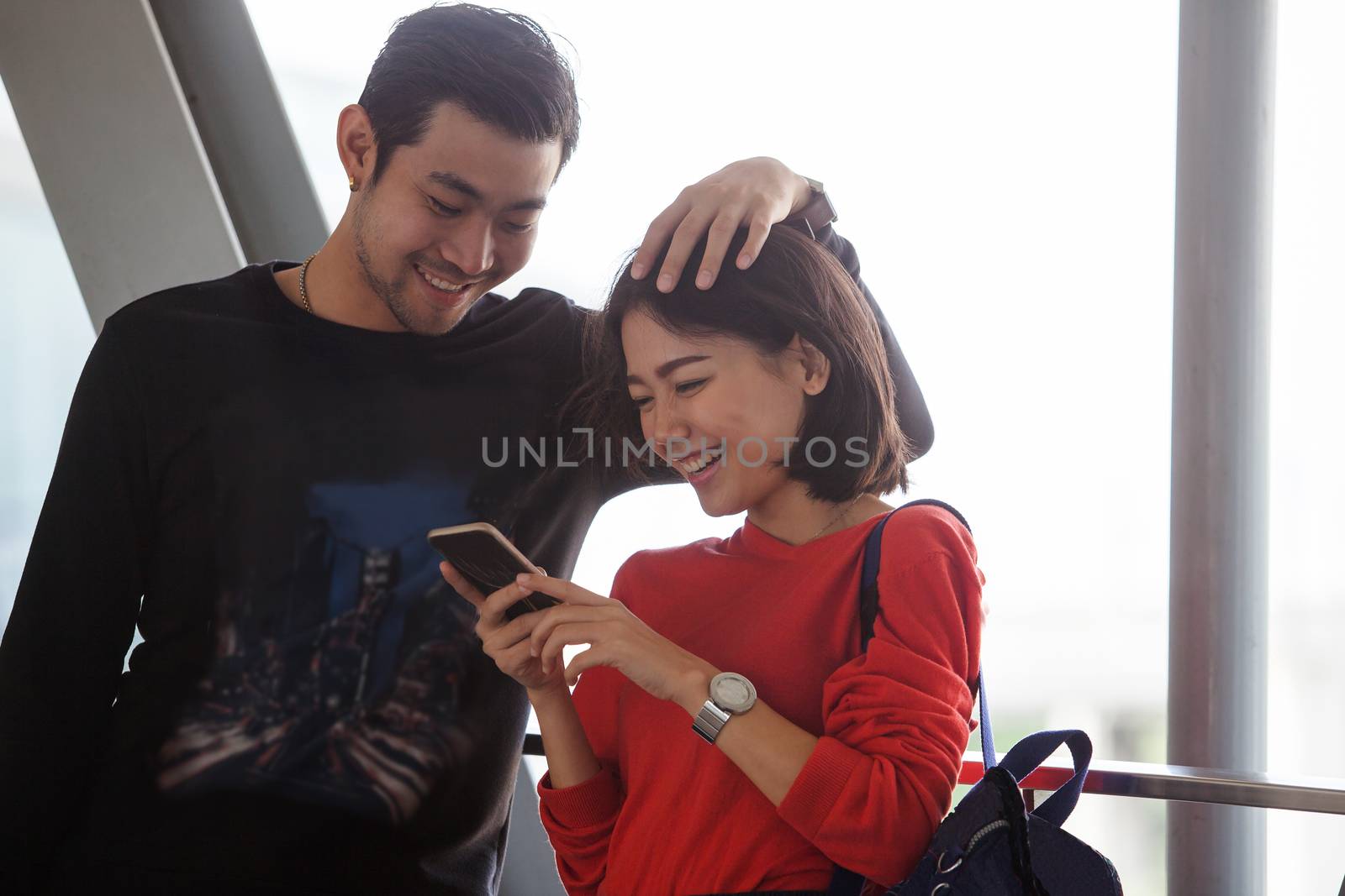 couples of younger asian man and woman relaxing with happy face reading text on smart phone use for people and modern lifestyle 