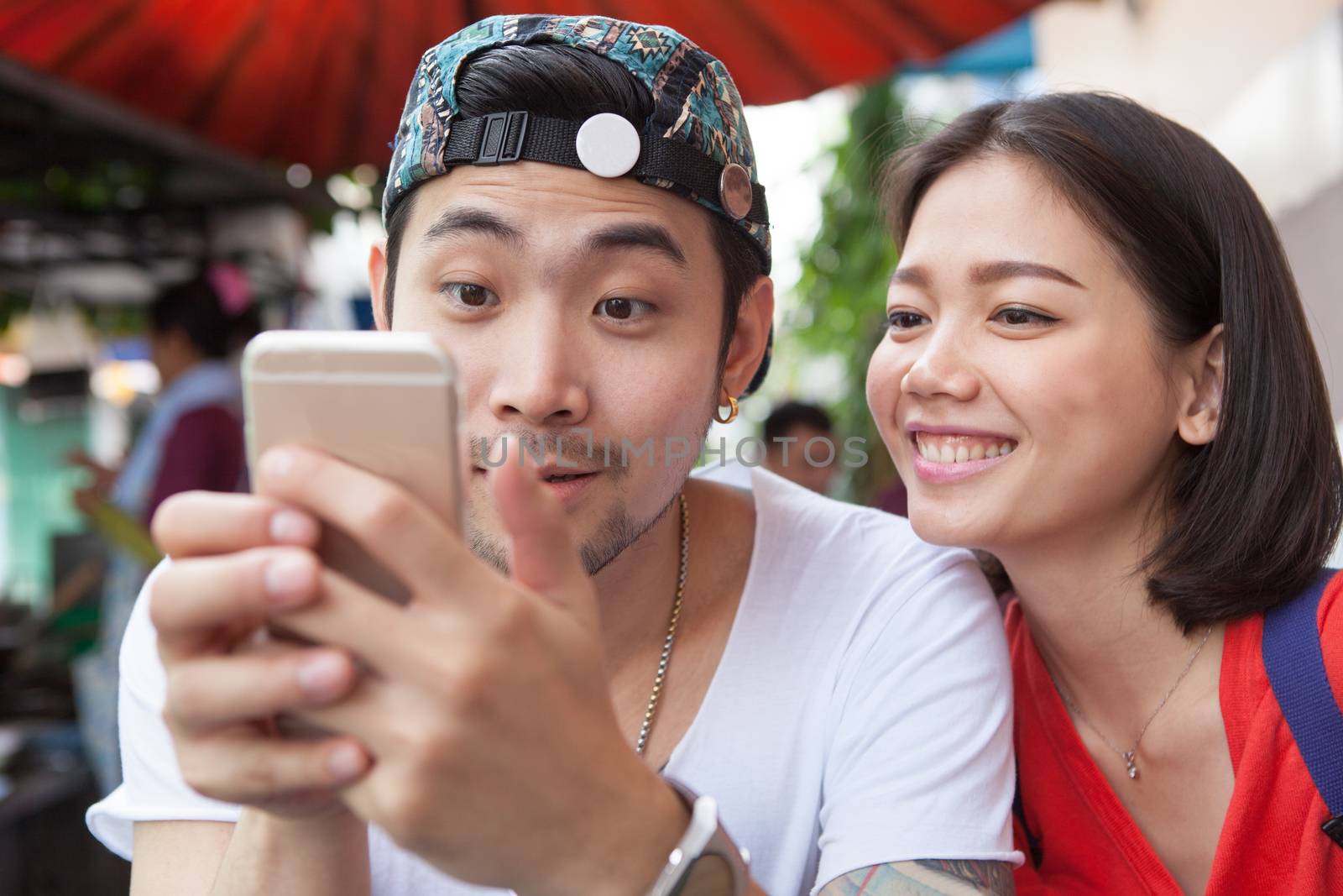 asian younger man and woman watching on smart phone use for peop by khunaspix