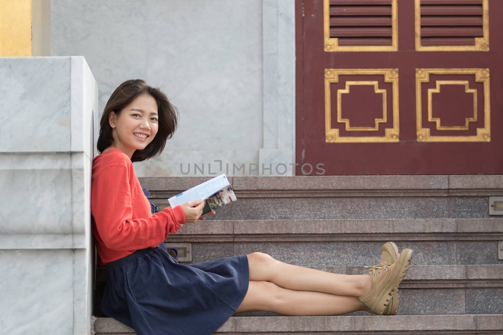 beautiful younger asian traveling woman relaxing and reading traveler guide book in thailand destination