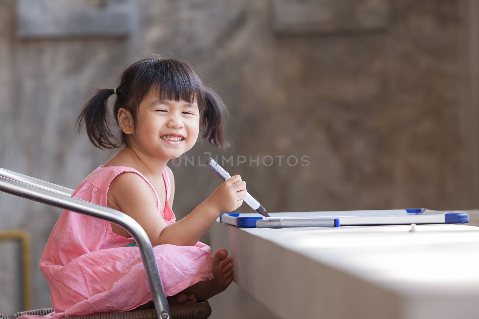 lovely face of toothy smiling asian children practive to writing on broad before going to school