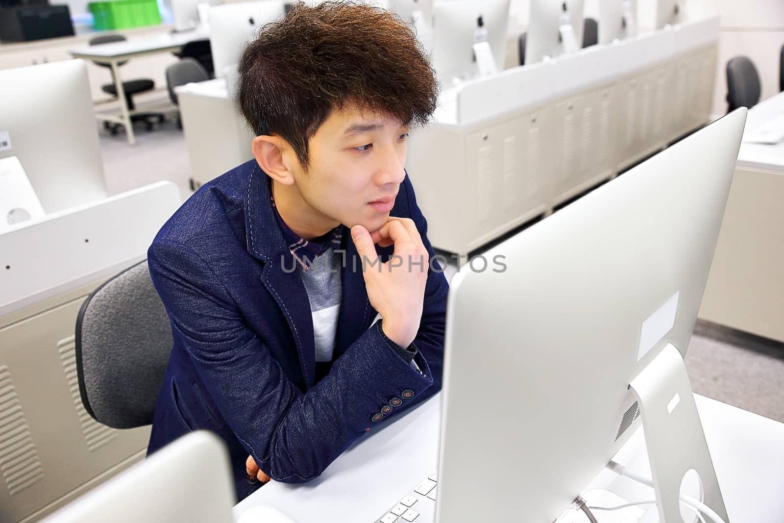 young man using computer in classroom by cozyta