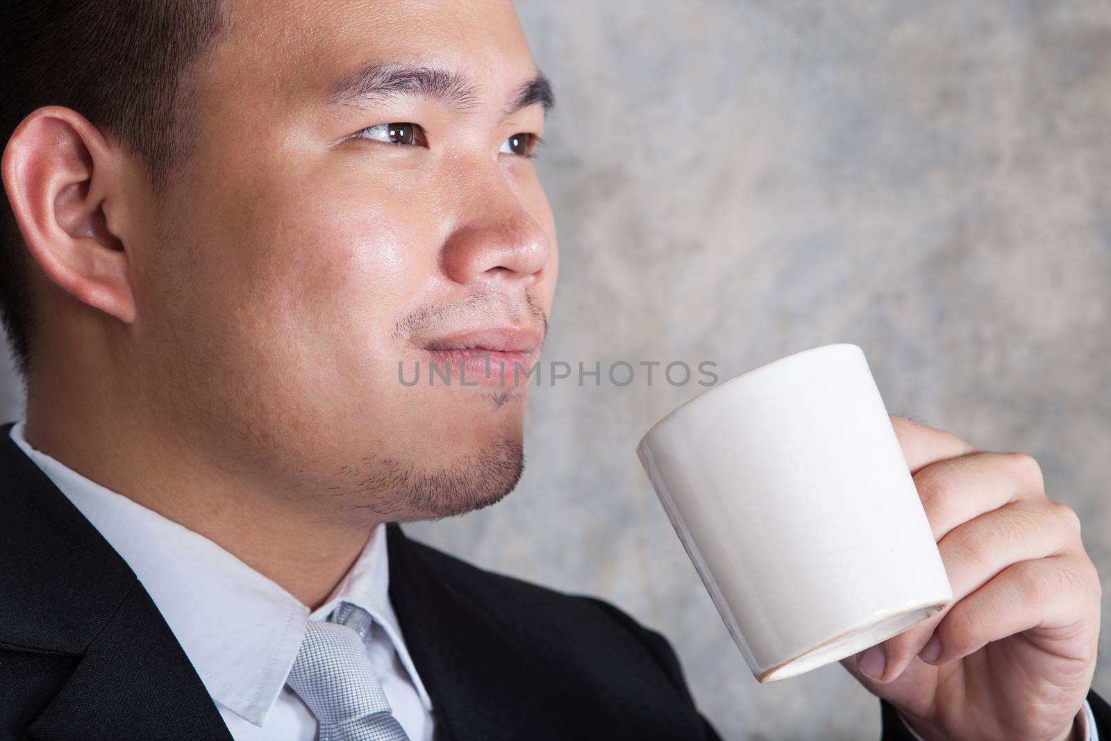 close up face of business man and ceramic coffee cup in hand with happiness emotion in eyes  