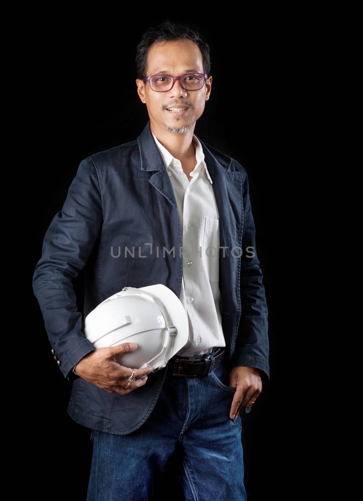 portrait of smiling face 45 years old asian working man in construction industry holding safety helmet standing against black background use for people occupation theme