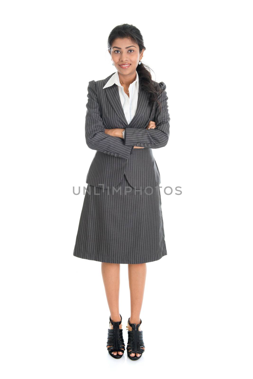 Full length portrait of Indian businesswoman standing arms crossed isolated on white background.