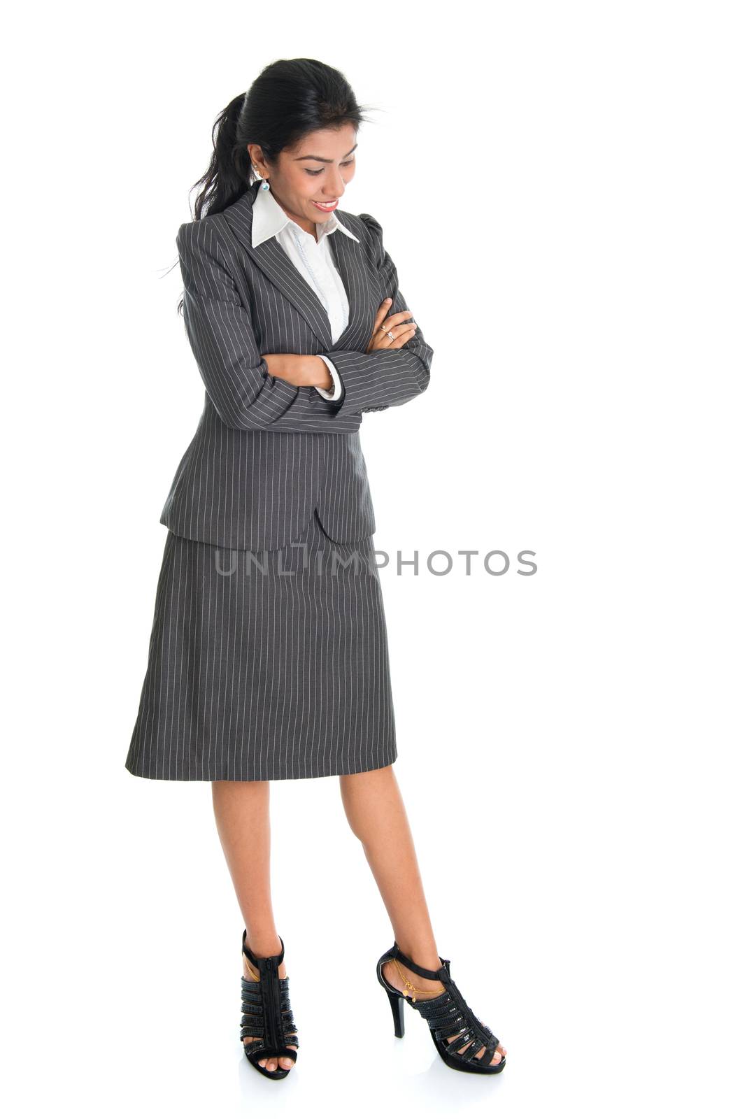 Full length portrait of African American businesswoman looking downward, standing arms crossed isolated on white background. 