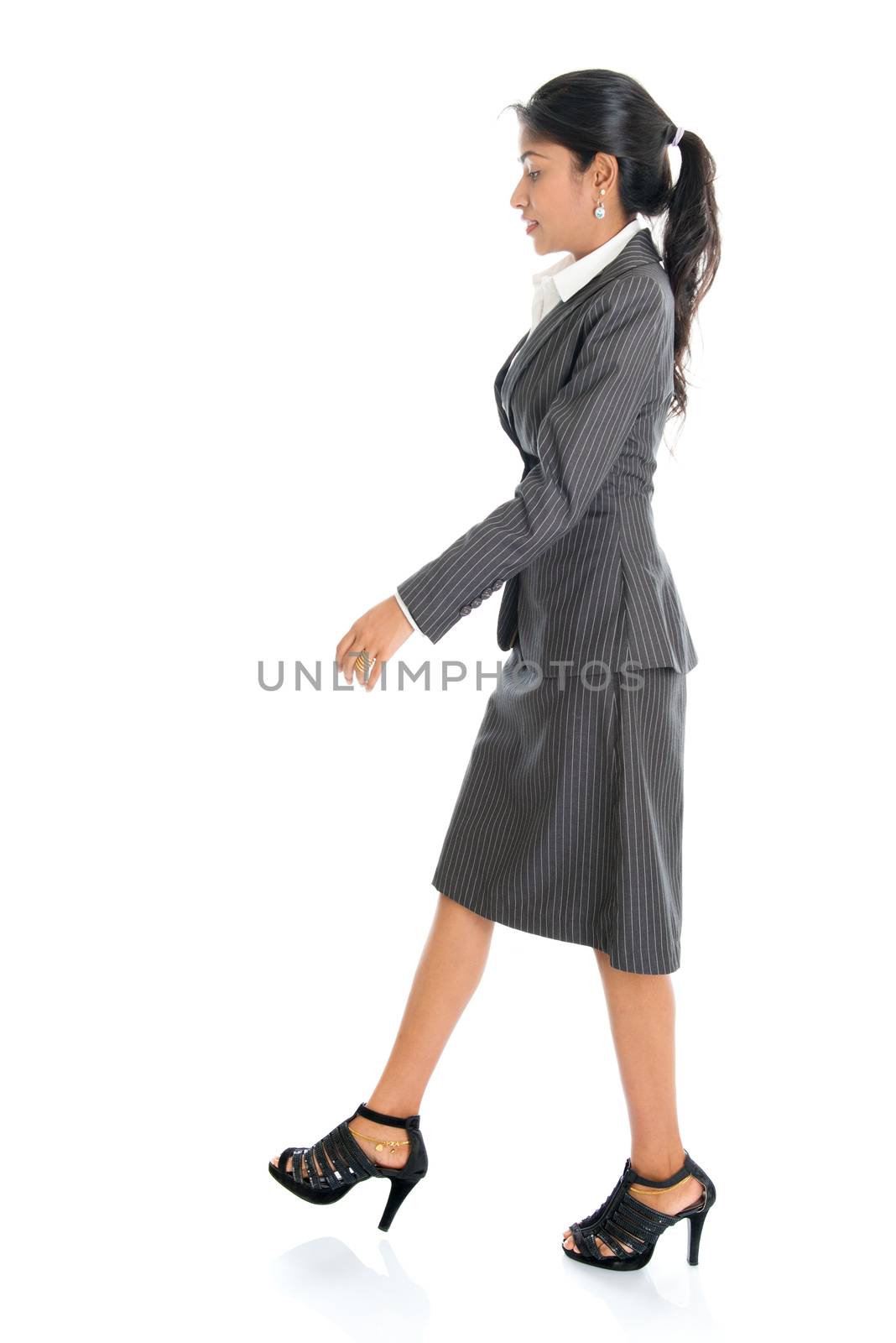 Full length side view of Indian businesswoman walking isolated on white background. 