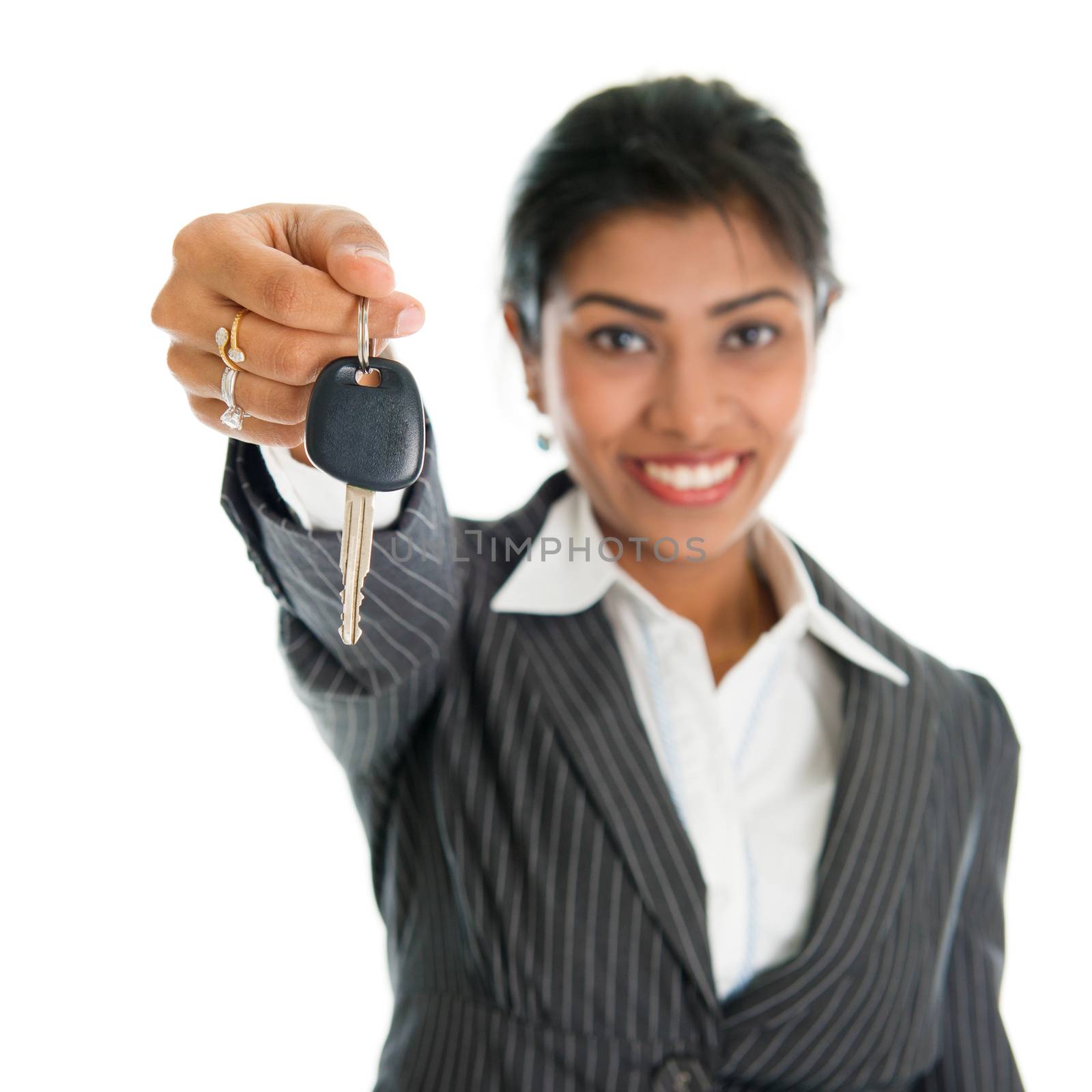 Indian woman showing car key and smiling, focus on key, isolated on white background.