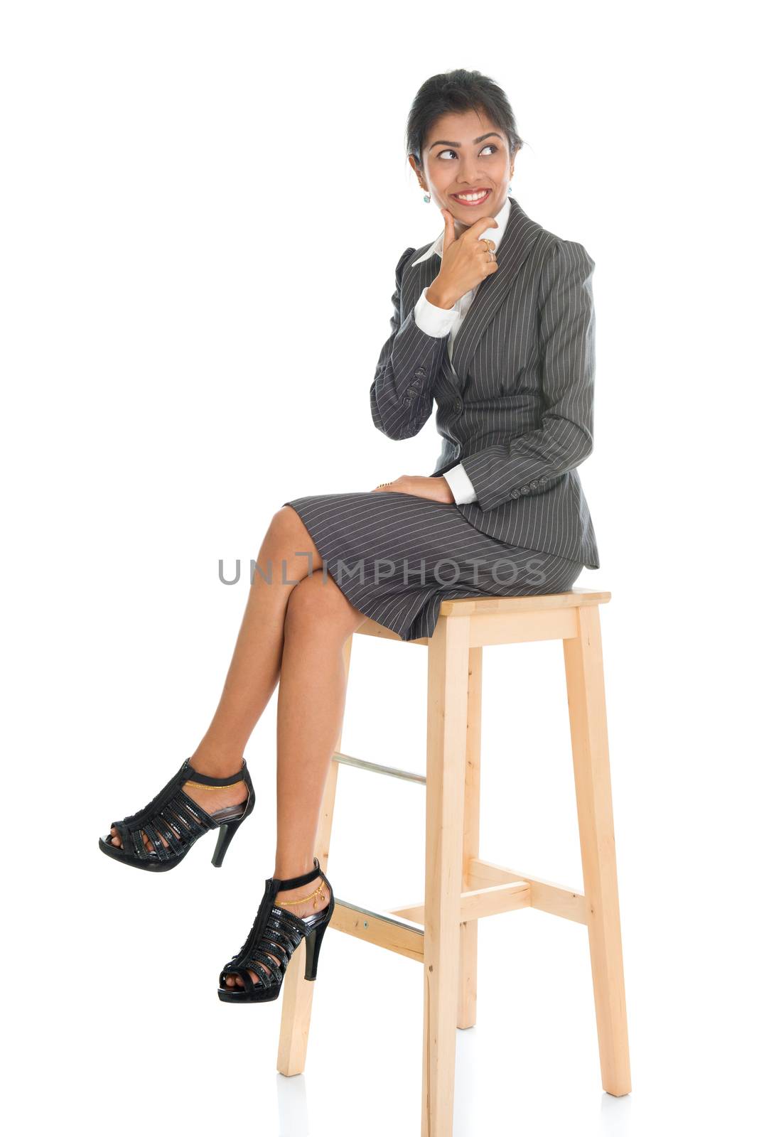 Full length black businesswoman sitting on high chair and having a thought, isolated on white background.