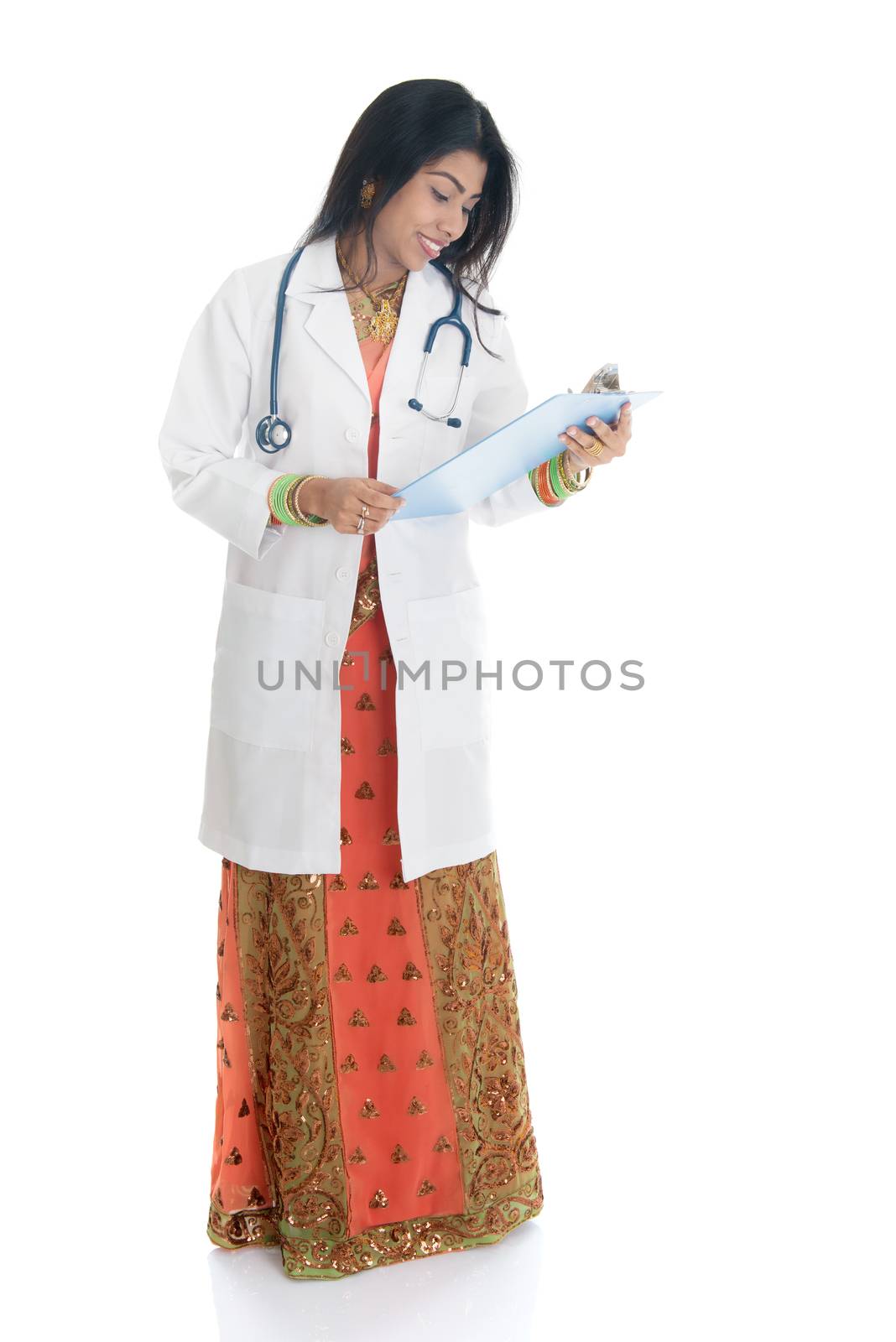 Portrait of full body Indian female doctor with medical test report, standing isolated on white background.