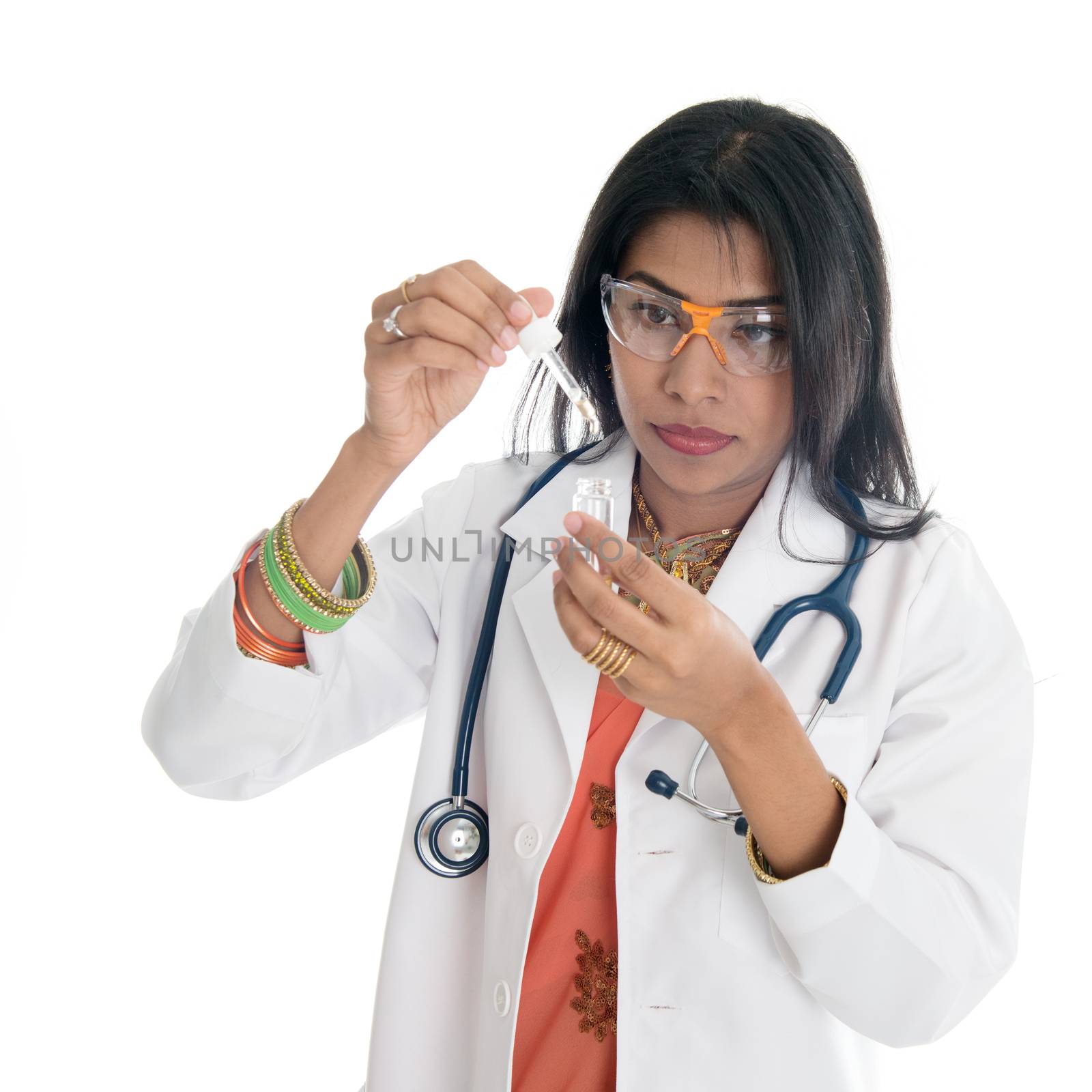 An Indian female medical or scientific researcher or woman doctor looking at a test tube of clear solution in a laboratory.