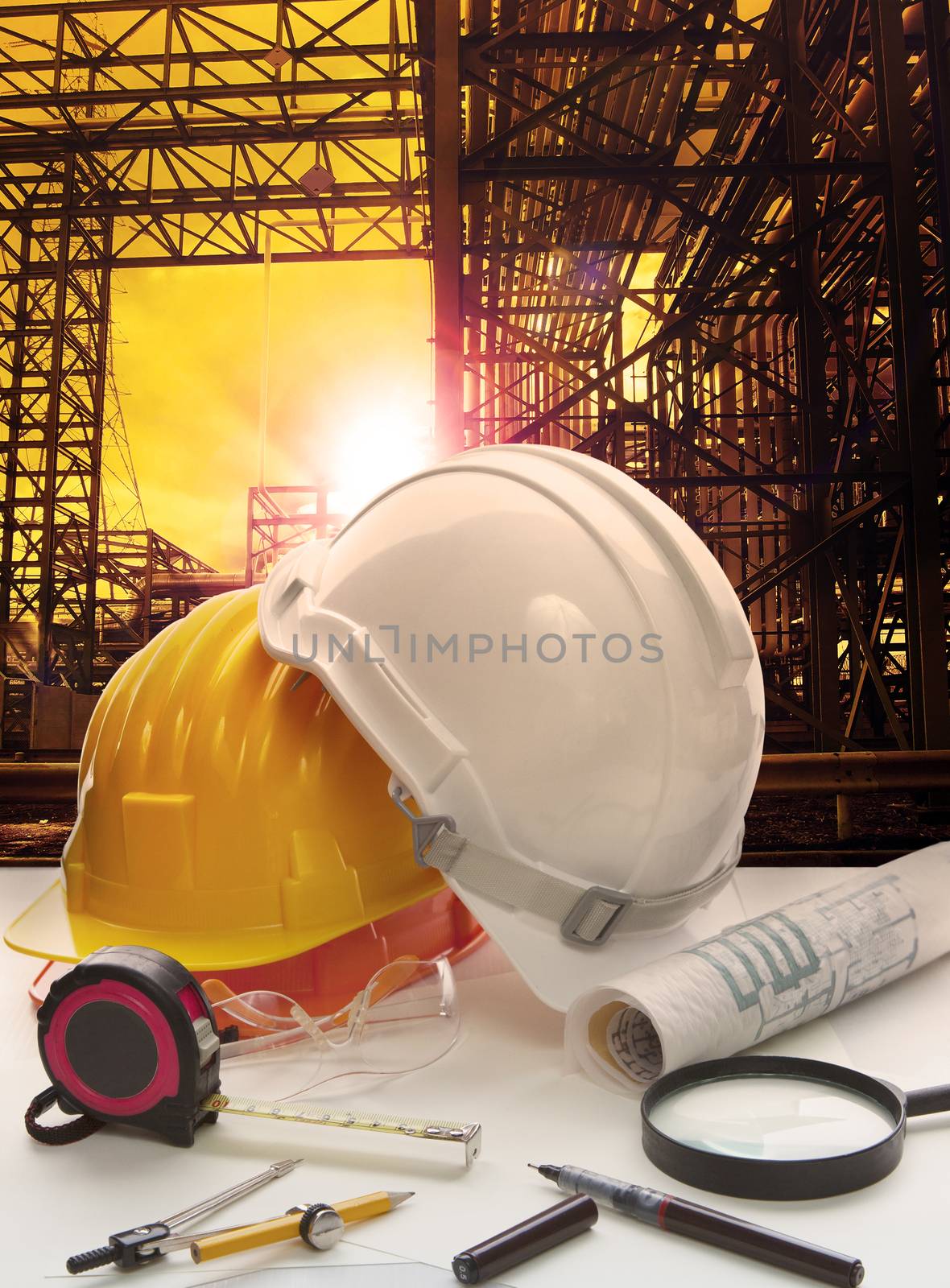 safety helmet on engineer working table against pipe line structure in heavy petrochemical industry estate