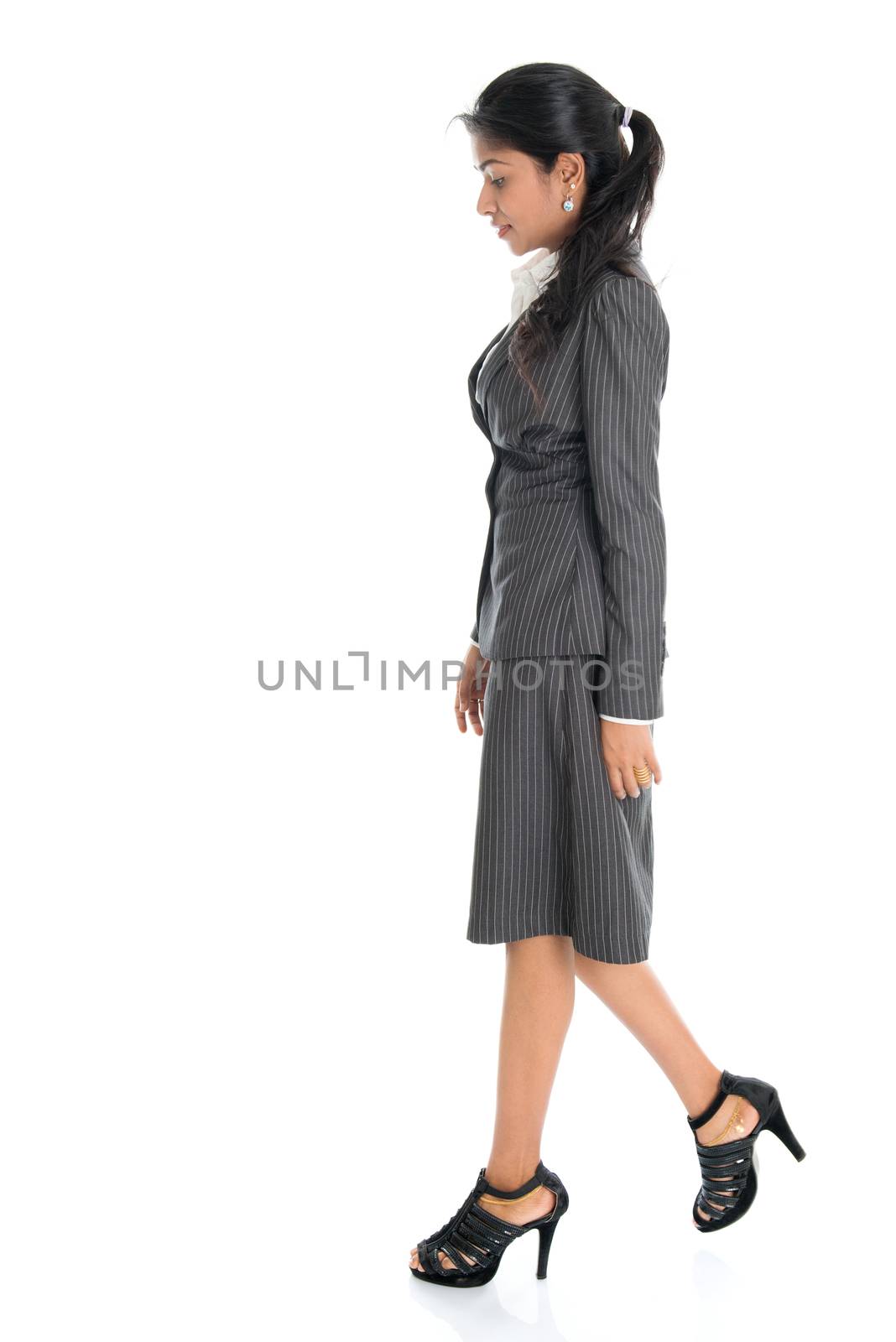 Full length side view of Indian business woman walking isolated on white background. 