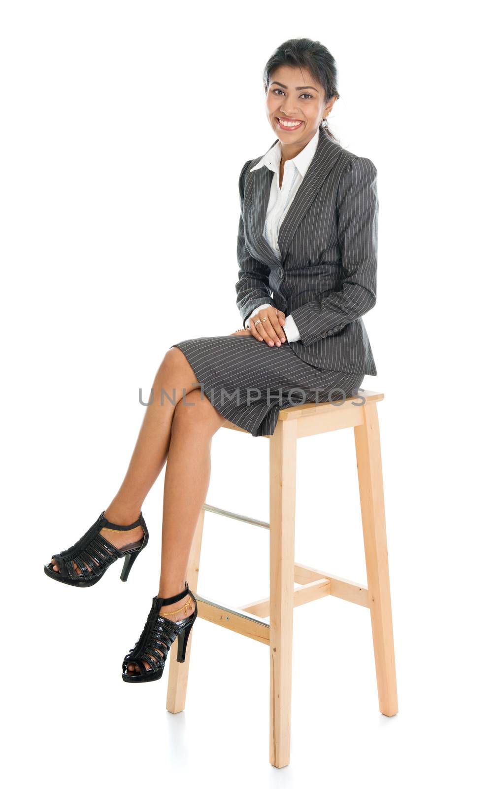 Full length black businesswoman sitting on high chair and smiling, isolated on white background.
