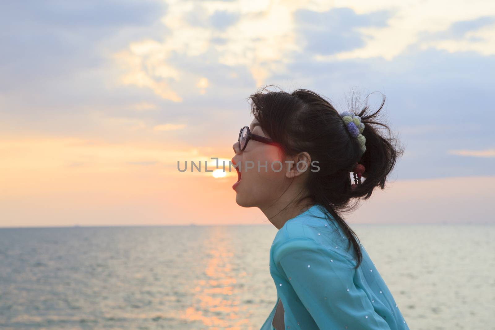 younger asian woman open mouth with sun set sky background
