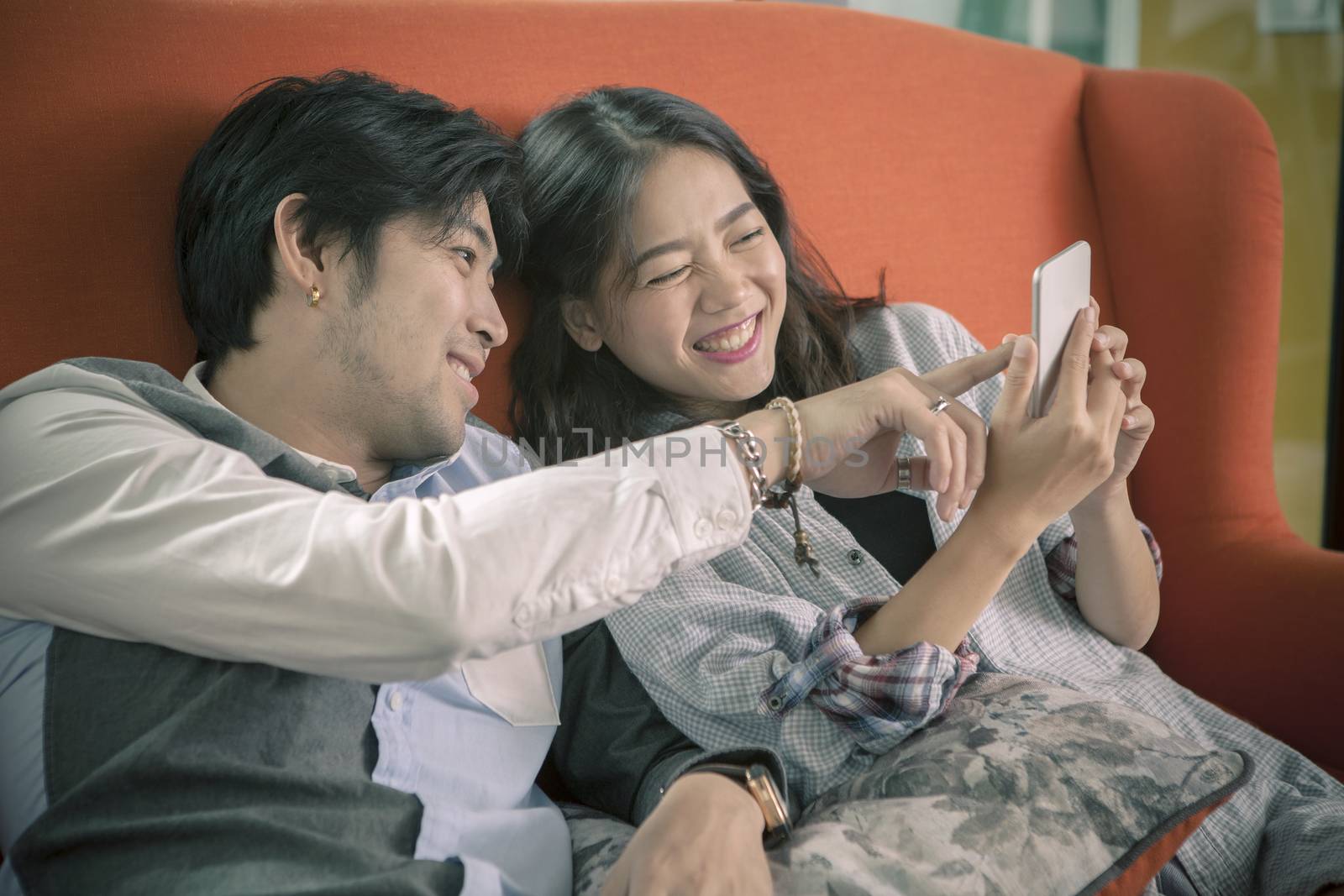 asian younger man and woman watching on smart phone with happy face,internet and social media connecting concept