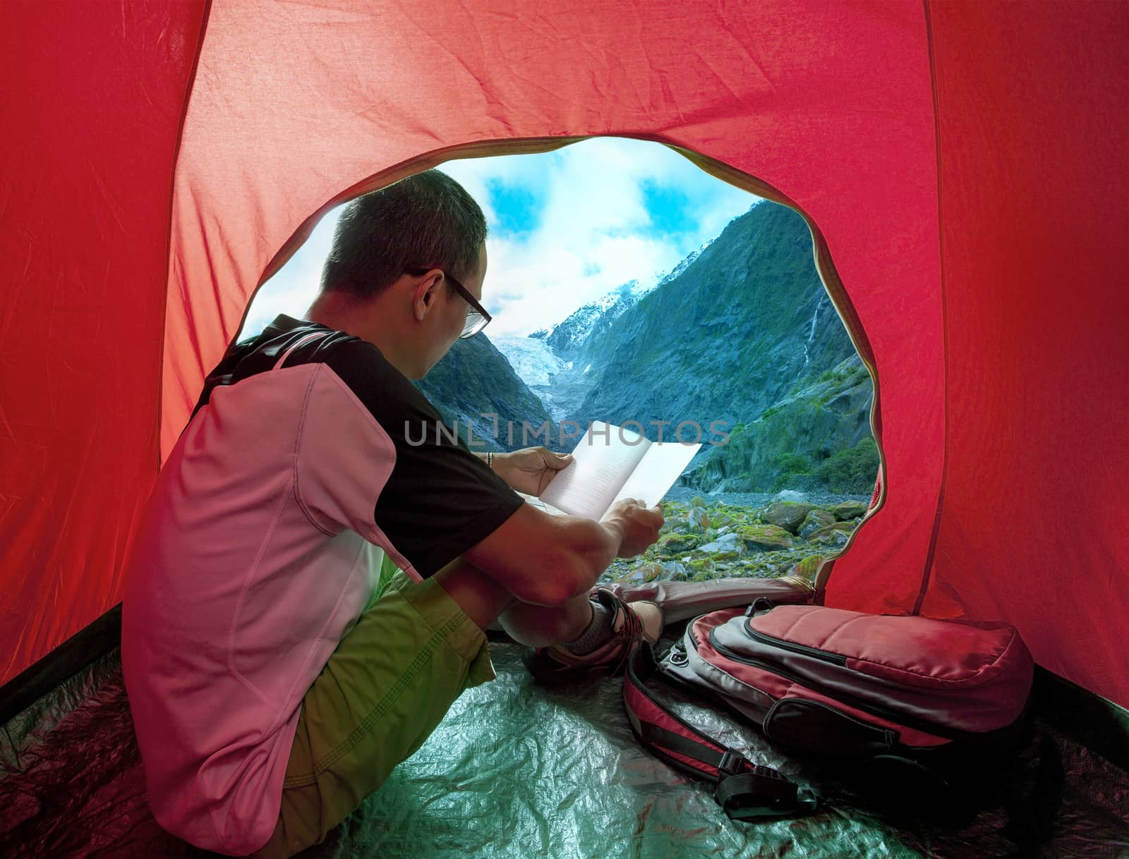 camping man reading a traveling guild book in camp tent beautiful mountain scenic