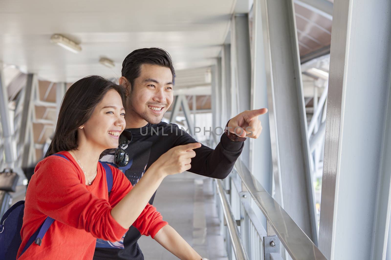 couples of younger asian traveling man and woman looking and pointing to tourist destination place smiling face happiness emotion