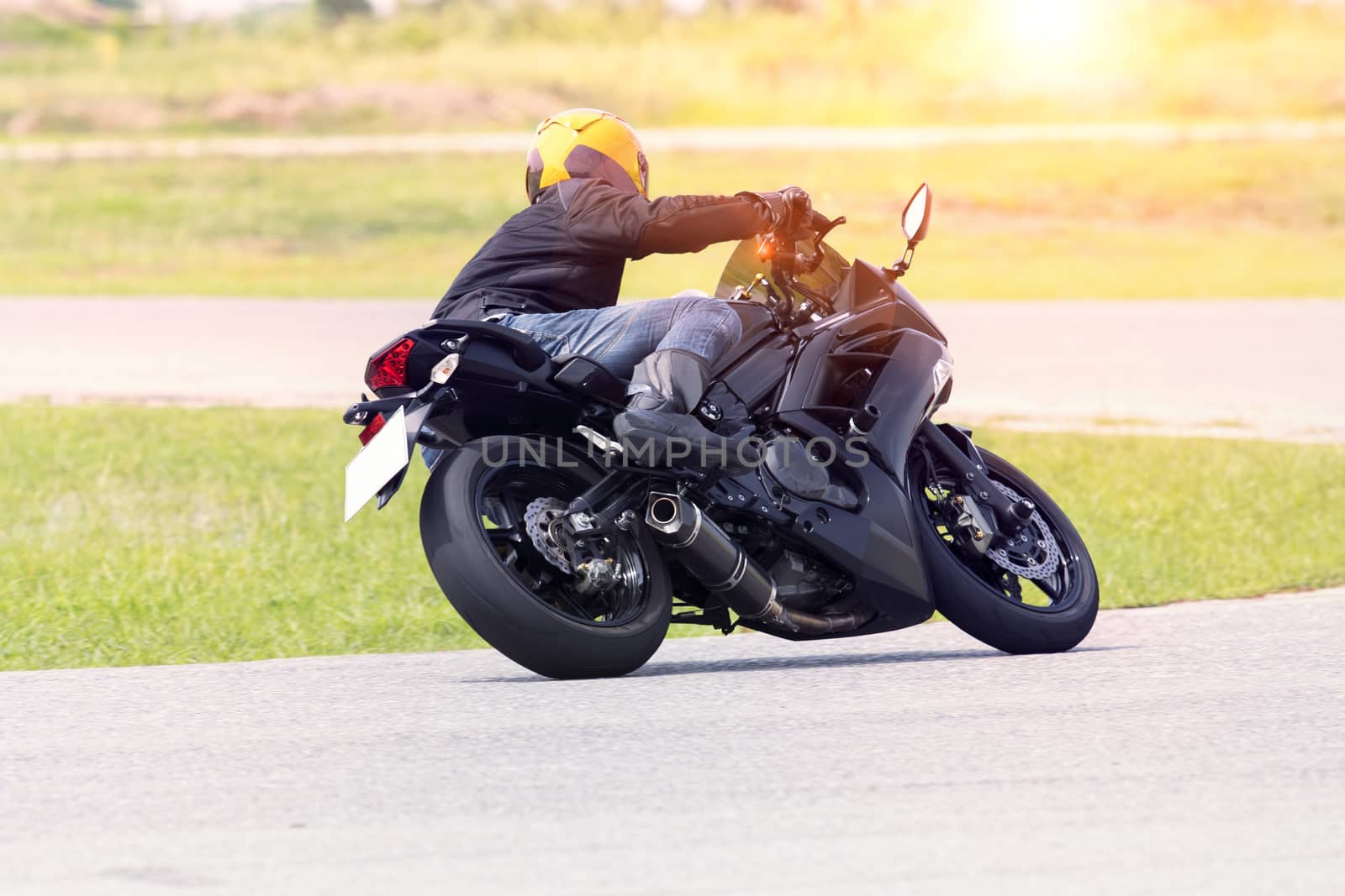 young man riding motorcycle in asphalt road curve wearing full safety suit 