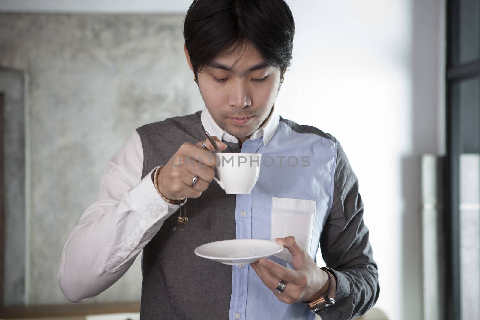 asian younger man drinking hot beverage in white cup 